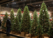 Artificial Christmas tree decorated with ornaments and lights in a cozy Canadian living room